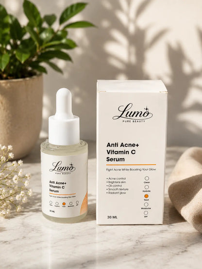 Lumo Pure Beauty Anti Acne+ Vitamin C Serum bottle with dropper next to its white product box, styled on a marble surface with a potted plant and beige cloth in the background.